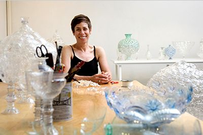 Image of Shari Mendelson in her studio surrounded by vessels made from recycled bottles.