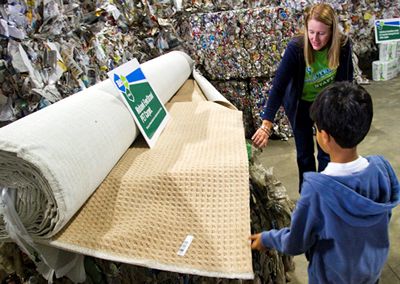Image of Stephanie Carr, executive assistant at ReCommunity, shows a young Morris County resident the spectrum of the recycling process, including bales of PETE bottles and carpet made from PETE at the October 1 grand opening of the ReCommunity Morris single-stream materials recovery facility.