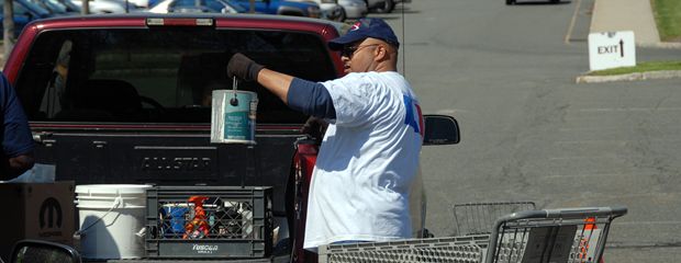 Image of holding paint can up at the trunk of a car